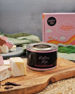 Marshmallow toaster canister with 'Mallow Mia' branding on a wooden board with marshmallows and a pink box in the background.