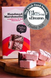 Handmade raspberry marshmallow with chocolate drizzle on a wooden board with 'Blas na hEireann' award badge.